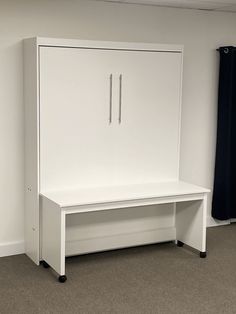 an empty room with a white cabinet and black curtains