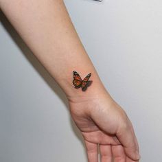 a woman's arm with a small butterfly tattoo on the left side of her wrist