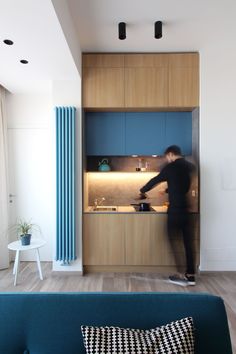 a person standing in front of a kitchen with blue cupboards and counter tops on the wall