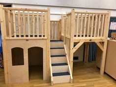 there is a wooden play house with stairs and a ramp to the second floor that leads up