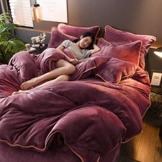 a woman laying on top of a bed covered in purple comforter and pillow covers