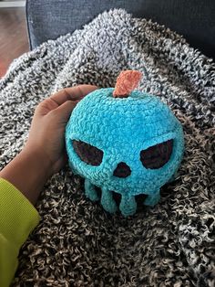 a person holding a blue stuffed animal on top of a bed