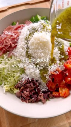 someone pouring dressing into a salad in a bowl