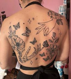 the back of a woman's body with butterflies and flowers on it