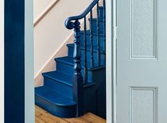 a blue stair case next to a white door