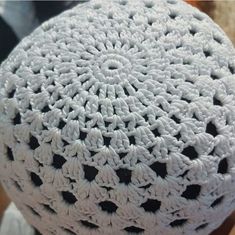 a white crocheted cushion sitting on top of a wooden table