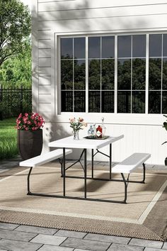 a white picnic table sitting on top of a patio next to a potted plant