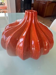 an orange vase sitting on top of a glass table