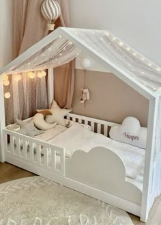 a white doll house bed with lights on the ceiling and curtains hanging from the windows