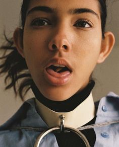 a woman wearing a collar with a metal ring around her neck, making a surprised face