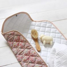 a baby's sleeping bag with a wooden brush and toy sheep on the floor