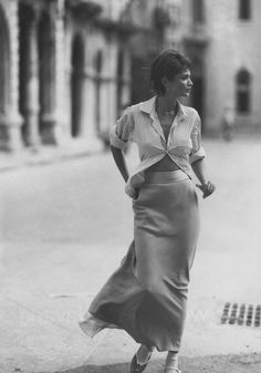 an old photo of a woman walking down the street with her hands on her hips