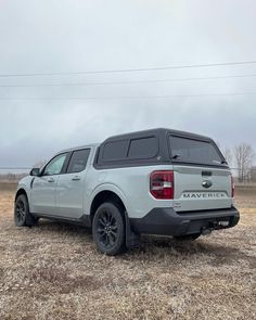 a white truck parked on top of a dry grass field