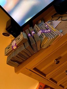 stacks of money sitting on top of a wooden dresser next to a flat screen tv