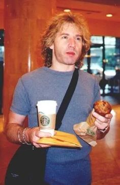 a man holding a bagel and cup of coffee