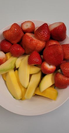 a white plate topped with sliced up strawberries and apples