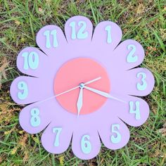 a purple clock with numbers on it sitting in the grass