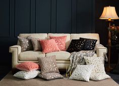 a living room filled with lots of pillows on top of a carpeted floor next to a lamp