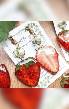 three strawberry shaped earrings on top of a card