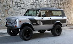 an off - road vehicle is parked in front of a brick wall with black rims