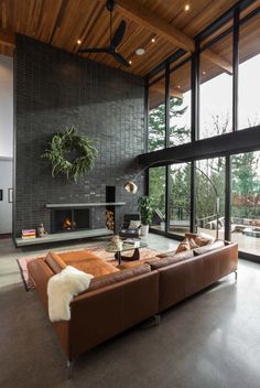 a living room with large windows and a couch in front of a fire place that has a potted plant on top of it