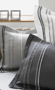 two pillows on a bed with black and white striped pillow cases next to each other