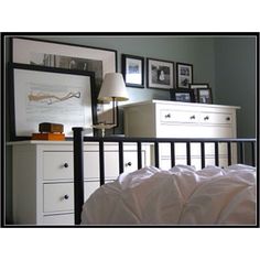 a bedroom with white furniture and pictures on the wall