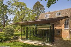 a glass walled building in the middle of a park