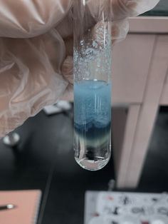 a hand holding a test tube filled with blue liquid and white flecks on it