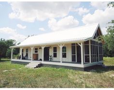 a small white house sitting on top of a lush green field