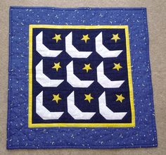 a quilted wall hanging with stars and crescents in the center on a carpet