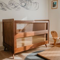 a baby crib in the corner of a room next to a wall with waves painted on it