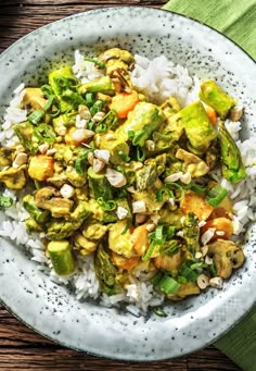 a white plate topped with rice and veggies on top of a wooden table