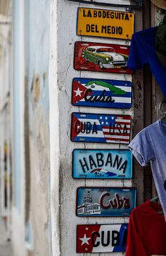 several signs are hanging on the side of a building with clothes and t - shirts