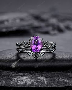 a ring with an amethorate stone in the center on top of a rock