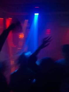 people are dancing at a party with their arms in the air and lights on behind them