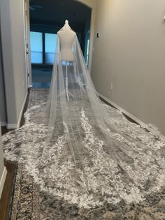 a wedding dress on display with a veil over it's head in a hallway