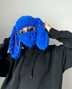 a person wearing a blue knitted animal mask covering their face with sunglasses on top of his head