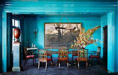 the dining room is painted bright blue and has chairs around it, along with a painting on the wall