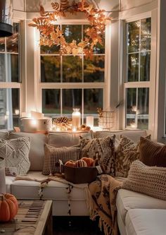 a living room filled with lots of furniture next to a window covered in fall decorations