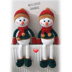 two knitted snowmen sitting on top of a radiator next to each other