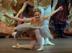 a young ballerina is posing for the camera with her arms outstretched in front of other dancers