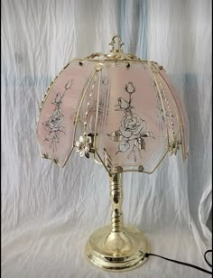 a lamp that is on top of a white cloth covered tablecloth with flowers and vines