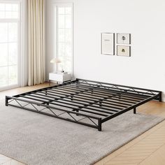 a metal bed frame sitting on top of a wooden floor next to a white wall