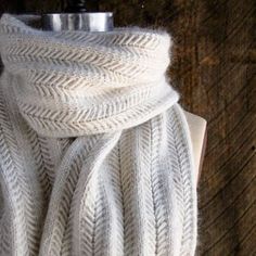 a close up of a white scarf on top of a wooden table next to a bottle