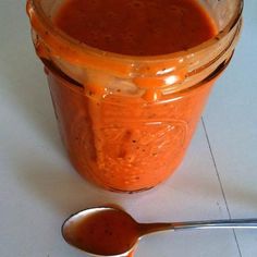 a spoon sitting next to a jar filled with sauce