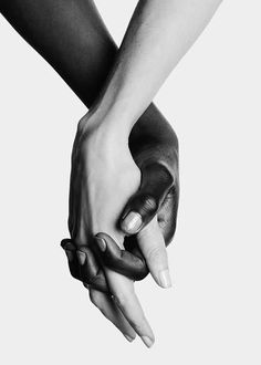 black and white photograph of two people holding each other's hands with their fingers