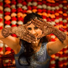 a woman holding her hands up to her face with hendi tattoos on it's arms