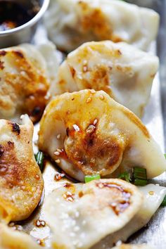 some dumplings with sauce and green onions on a sheet of tin foil, ready to be eaten