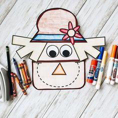 an image of a paper doll with crayons on the table next to it